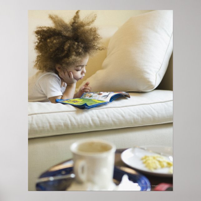 Mixed race boy reading book on sofa poster (Front)