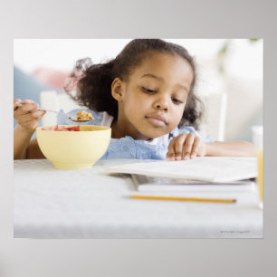 Mixed race girl reading and eating breakfast poster