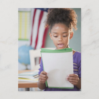 Mixed race girl reading report at school postcard