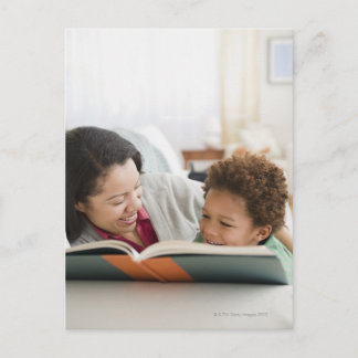 Mixed race mother reading book to son postcard
