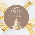 Mocha cream beige tree Christmas Classic Round Sticker<br><div class="desc">A mocha,  muted brown coloured background.  Decorated with a snowcovered tree.  Merry Christmas is written with an elegant hand-lettered style script.  Personalise and add your family name. Cream,  beige coloured text.</div>