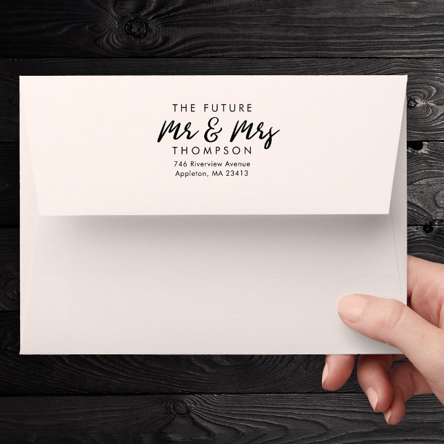 Modern 5x7 Script The Future Mrs and Mr Preprinted Envelope (A hand holds a white envelope against a dark wooden background. The envelope is printed)