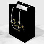 Modern Black and Gold Personalised Bridesmaids Medium Gift Bag<br><div class="desc">Modern Black and Gold Personalised Bridesmaids Gifts featuring personalised bridesmaid's name in gold modern script font style with title and wedding date in modern sans serif font style on black background. Also perfect for Maid of Honour, Flower Girl, Mother of the Bride and more. Please Note: The foil details are...</div>