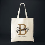 Modern Monogram Name  Black Gold Script Bridesmaid Tote Bag<br><div class="desc">The Modern Elegant Monogram Name Black Gold Script Tote Bag combines sophistication with practicality. This tote features a sleek black fabric adorned with elegant gold script monogramming, making it both stylish and personalised. The spacious interior is perfect for daily essentials, while the sturdy handles ensure comfort and durability. Ideal for...</div>
