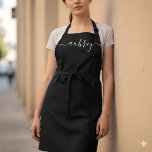 Monogram Script Handwritten Minimal Black Apron<br><div class="desc">Step into a world where each stroke of the pen tells a story – your story. Our custom aprons, adorned with your name inscribed in a modern script handwritten font, are not merely protective wear but a canvas that reflects your unique identity. Experience the elegant blend of contemporary style and...</div>