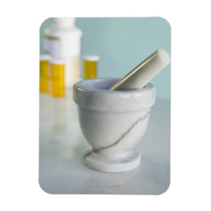 Mortar and pestle, pill bottles in background magnet