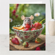 Mouse enjoys a strawberry in a dish of fruit