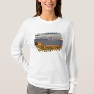 Old barn framed by hay bales and dramatic T-Shirt
