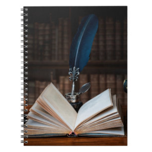 Old books, quill pen and vintage inkwell on wooden notebook