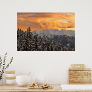 Orange clouds above mountains and spruce forest poster
