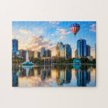 Orlando Florida Skyline Lake Eola Hot Air Balloon Jigsaw Puzzle<br><div class="desc">The digital design on this jigsaw puzzle features the Orlando Florida skyline reflecting in the waters of beautiful Lake Eola with its iconic fountain and amphitheater. Floating overhead is a hot air balloon in patriotic colors of red, white, and blue. Lake Eola Park in the heart of downtown Orlando is...</div>
