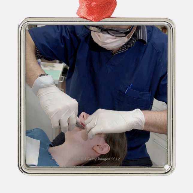 Orthodontist readjusting the dental braces of a metal tree decoration (Front)