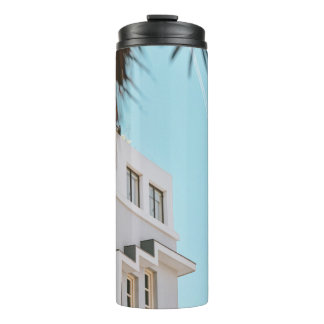 Palm tree near white concrete building thermal tumbler