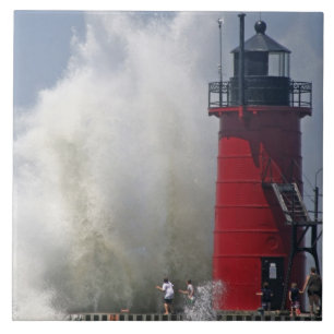 People on jetty watch large breaking waves in tile