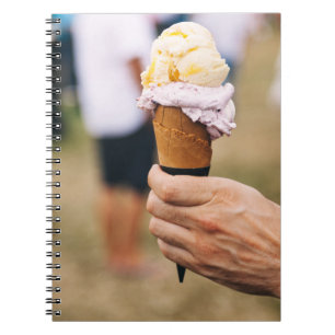 Person holding ice cream on cone notebook