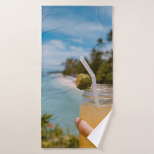 Person holding mason jar with filled with juice at bath towel