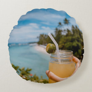 Person holding mason jar with filled with juice at round cushion