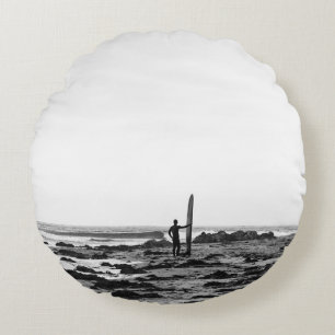 PERSON HOLDING SURFBOARD NEAR BODY OF WATER ROUND CUSHION