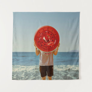 Person holding watermelon-themed inflatable ring tapestry