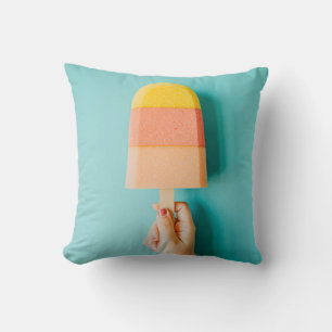 Person holding yellow and brown ice cream cone cushion