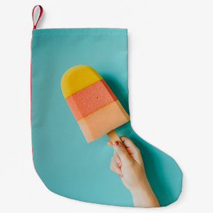 Person holding yellow and pink popsicle small christmas stocking