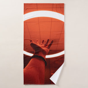 PERSON REACHING ROUND TURNED-ON FLUORESCENT LAMP I BATH TOWEL