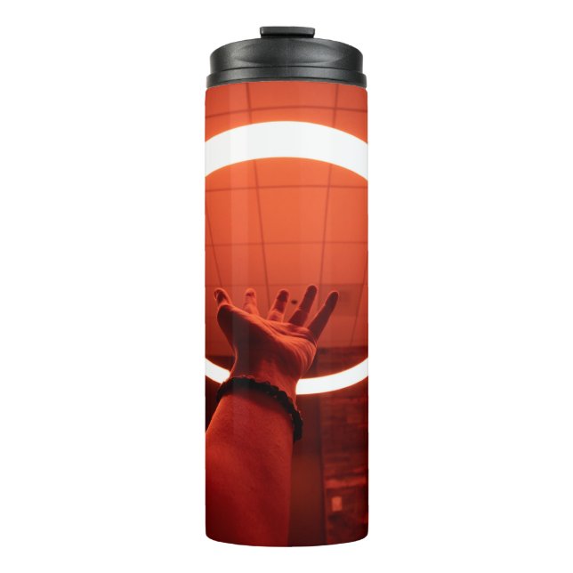 PERSON REACHING ROUND TURNED-ON FLUORESCENT LAMP I THERMAL TUMBLER (Front)