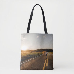 Person running in road in the morning tote bag