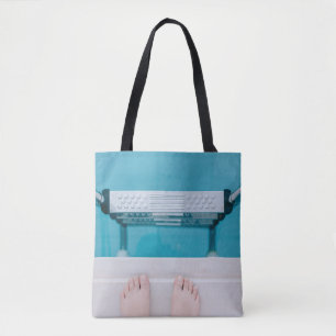 Person standing on swimming pool ladder tote bag