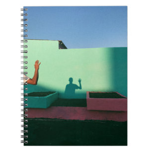 Person waving reflecting shadow on teal wall paint notebook