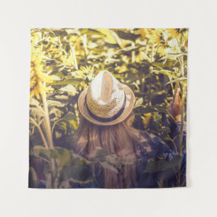Person wearing white hat beside sunflower fields tapestry