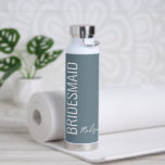 Personalised Bridesmaid Dusty Blue White Script Water Bottle<br><div class="desc">Surprise your wedding gal pals with this Personalised Bridesmaid Dusty Blue White Script Water Bottle. It is modern minimalist designed with a customisable blue background. The text is "bridesmaid" in big white lettering vertical on left front side. Name is in matching trendy hand lettered script on on right lower area....</div>