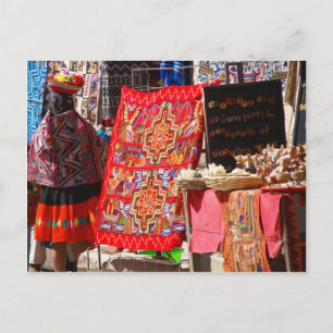 Peruvian Indian woman looking at colourful textile Postcard