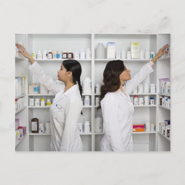 Pharmacists reaching for medication on shelves postcard (Front)
