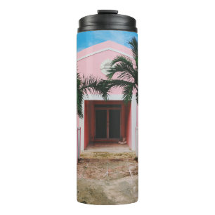 Pink and white concrete house near green trees und thermal tumbler