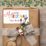 Playful White Merry Christmas Family Name Design Label<br><div class="desc">Add a festive touch with this playful white merry Christmas family name design, perfect for holiday celebrations. The cheerful text features a vibrant mix of red, yellow, pink, green, and blue letters, with a classic red family name below for a personal flair. Ideal for labelling holiday cards, party favours, or...</div>