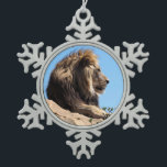 Portrait of lion seen from profile  snowflake pewter christmas ornament<br><div class="desc">Portrait of lion (Panthera leo) lying on rock and seen from profile on blue sky background</div>