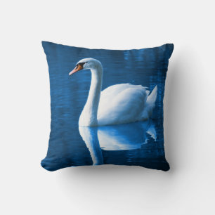 Pretty white swan floating on a blue lake cushion