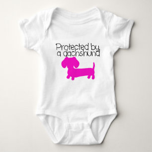 Protected by a Dachshund (pink) Baby Bodysuit