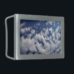 Puffy Clouds On Blue Sky Belt Buckle<br><div class="desc">A bank of puffy white clouds breaks into small wispy pieces across the frame of the vertical photograph. The cloud cover is denser on the left and more sparse on the right, revealing a deep blue sky that is dark near the top of the photo and lighter near the bottom....</div>