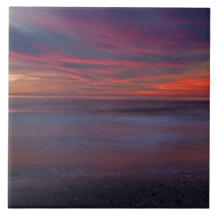 Purple-coloured sunrise on ocean shore tile