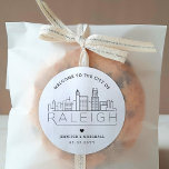 Raleigh Wedding | Welcome Favour Classic Round Sticker<br><div class="desc">Enhance your wedding welcome packages or event party favours with a custom set of welcome stickers! These elegant yet minimal-style stickers are tailored for a wedding taking place in the beautiful city of Raleigh, North Carolina. They feature a modern deco skyline with the name of the city integrated underneath. All...</div>