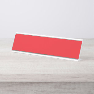 Red and orange crayons lying side by side on a whi desk name plate