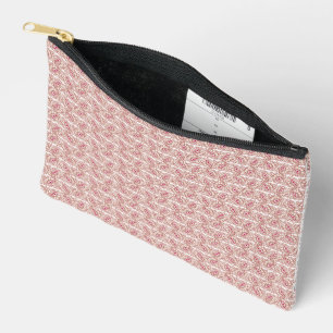 Red and pink textiles laid over a patterned rug wi accessory pouch