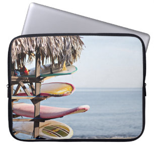 Red and white surfboard in brown wooden rack laptop sleeve