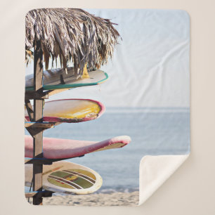 Red and white surfboard in brown wooden rack sherpa blanket