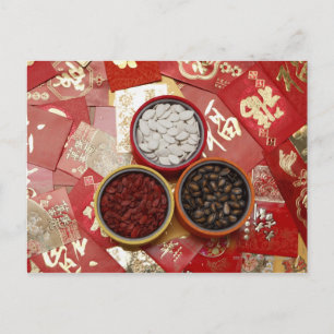 Red envelopes with melon seeds scattered on table postcard