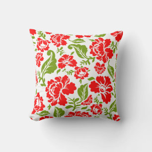 Red flowers with green leaves create a vibrant cushion