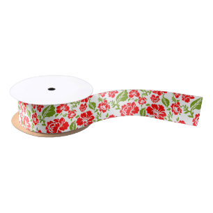 Red flowers with green leaves create a vibrant satin ribbon