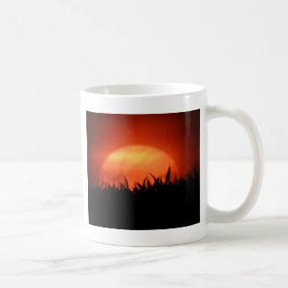 Red sundown behind black grass coffee mug
